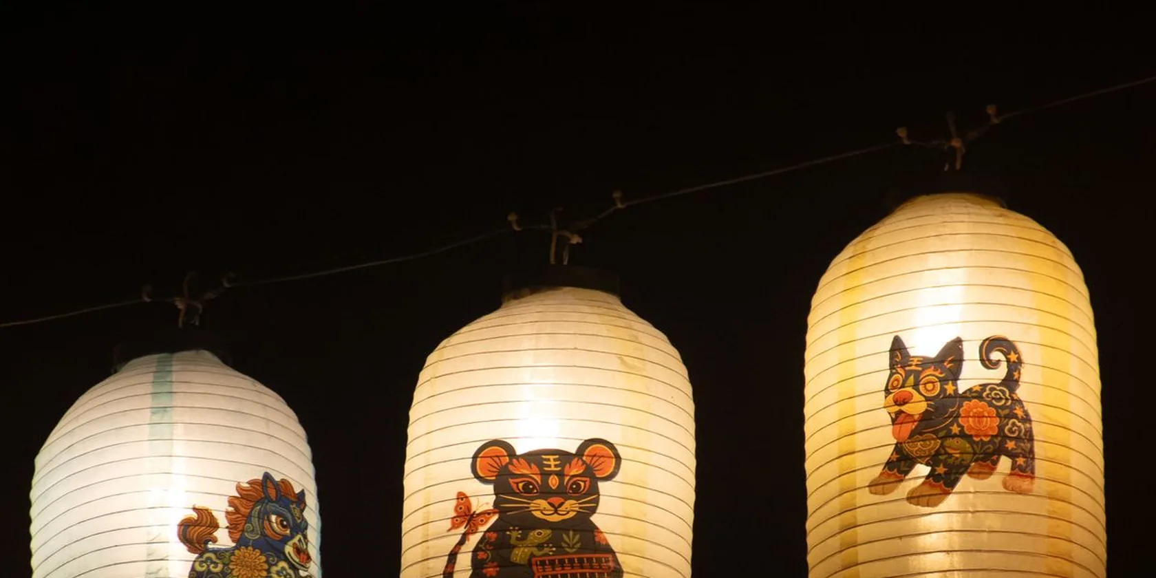 Trois lanternes chinoises illustrées d'animaux du zodiaque dans la nuit