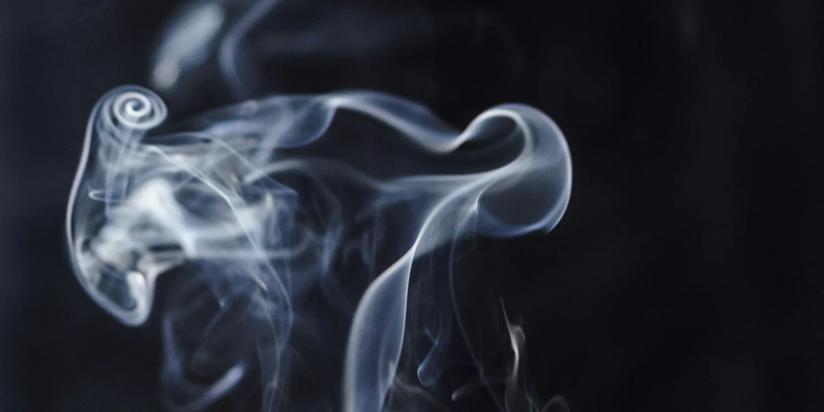 Volutes de fumée d'encens s'élevant dans l'obscurité