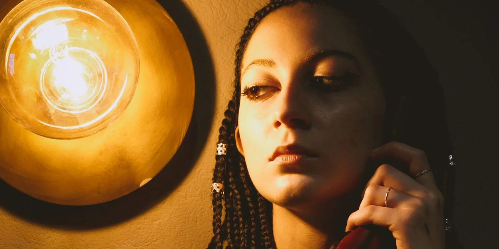 Femme éclairée par une lampe chaude tenant un combiné téléphonique vintage
